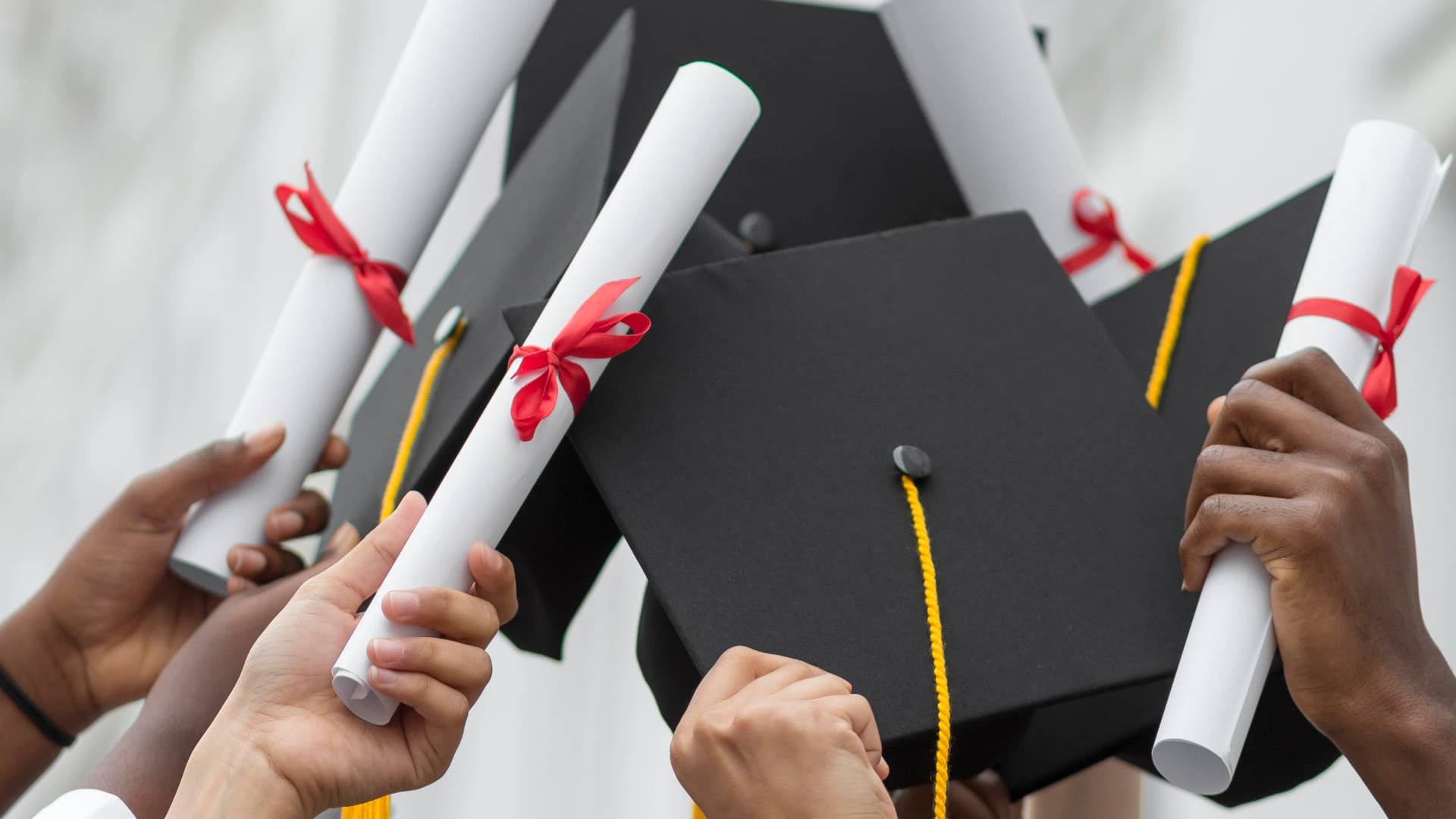 Graduates raising mortarboards and rolled diplomas